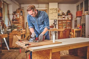 Person fräst Holzplatte mit Oberfräse